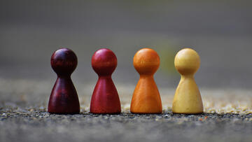Vier Spielfiguren mit unterschiedlichen Farebn auf rauem Untergrund