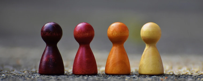 Vier Spielfiguren mit unterschiedlichen Farebn auf rauem Untergrund