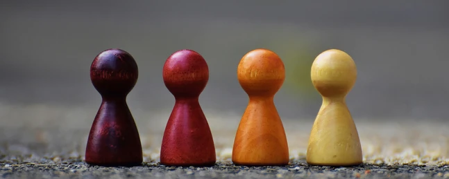 Vier Spielfiguren mit unterschiedlichen Farebn auf rauem Untergrund